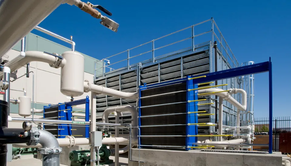 Blue-framed plate heat exchangers connected to white pipework outdoors